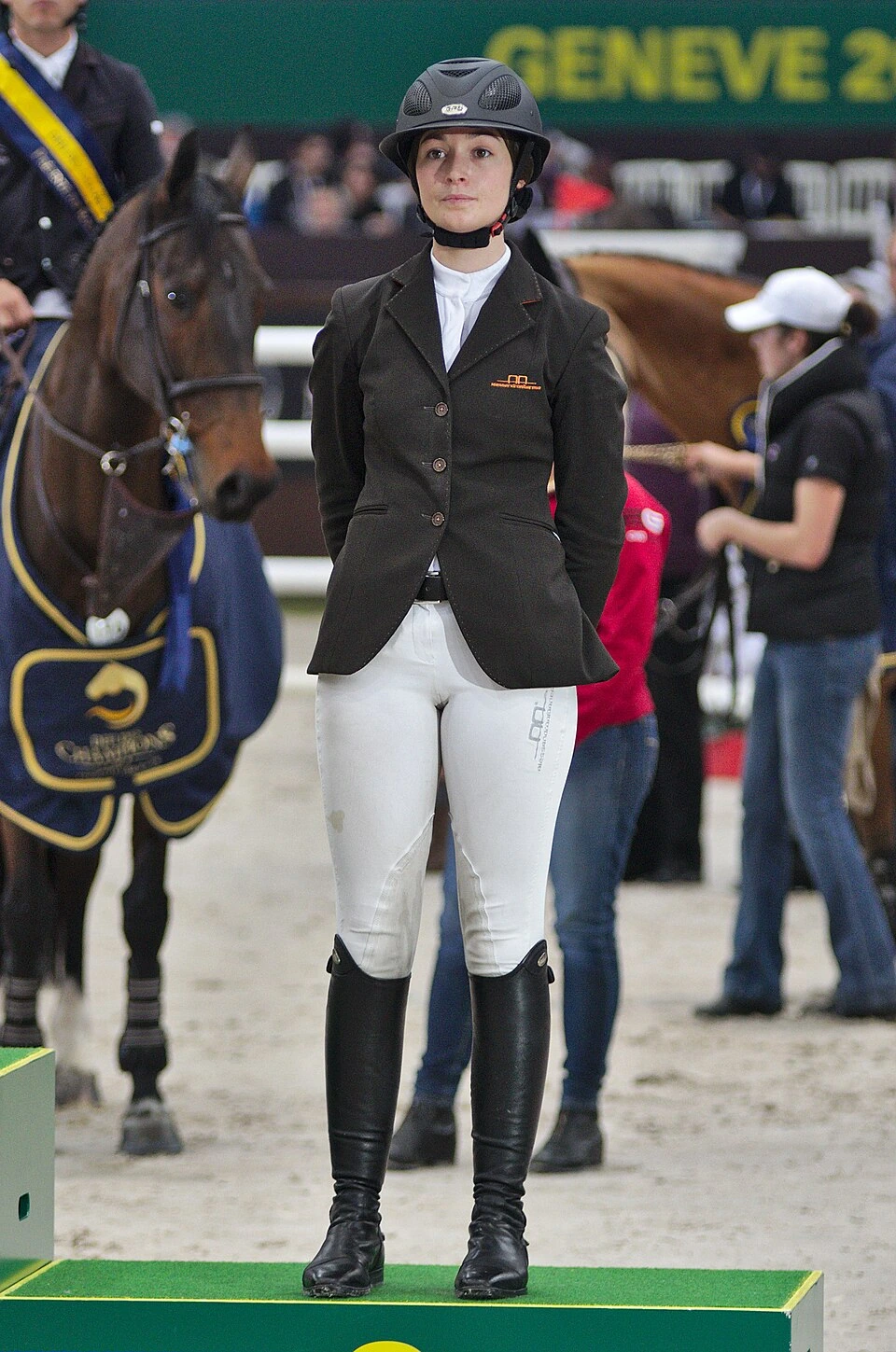 Reed Kessler standing in equestrian competition attire at an indoor show jumping event