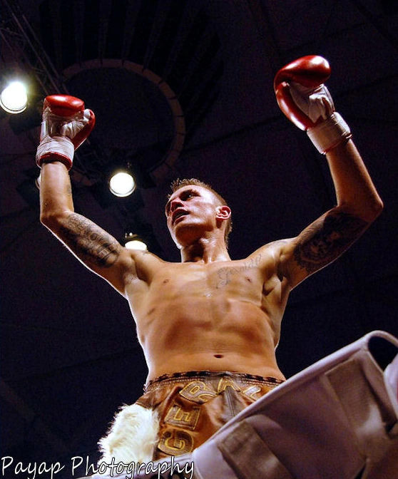 Nieky Holzken raising both gloves in the ring under arena lights