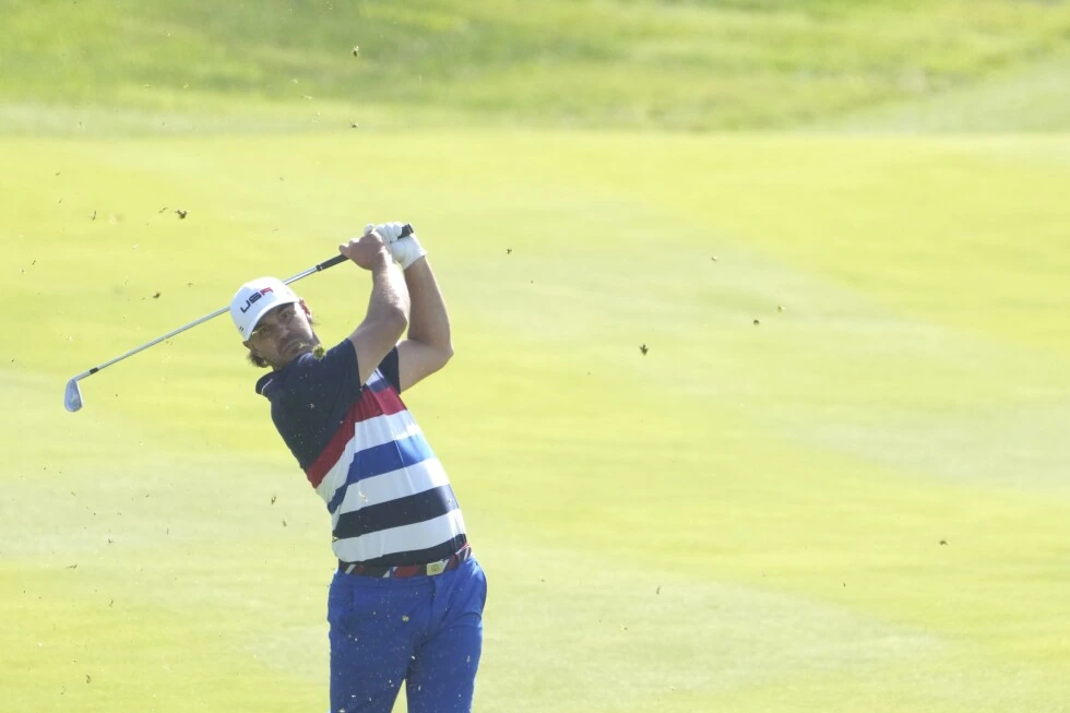 Brooks Koepka mid-swing on a golf course