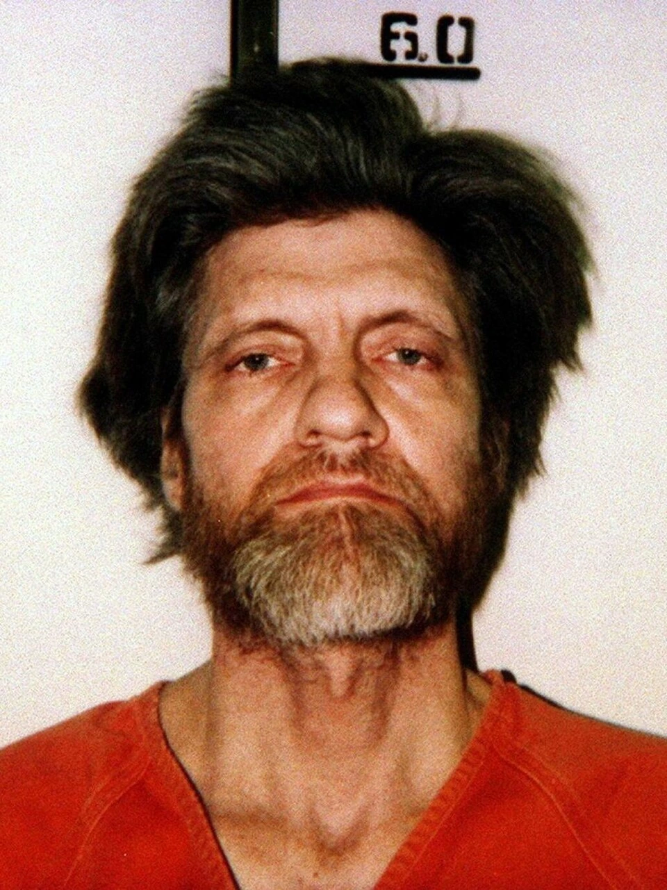 Mugshot of Ted Kaczynski in an orange prison uniform