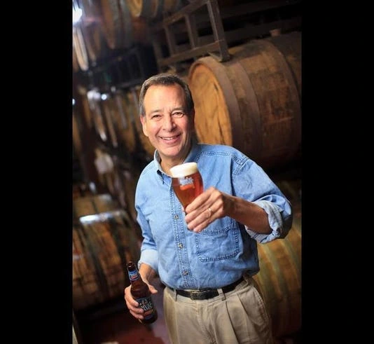 Jim Koch holding a beer in a brewery