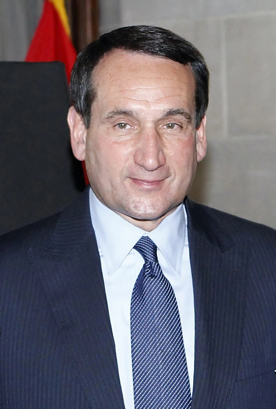 Mike Krzyzewski in a suit and tie, smiling at a formal event
